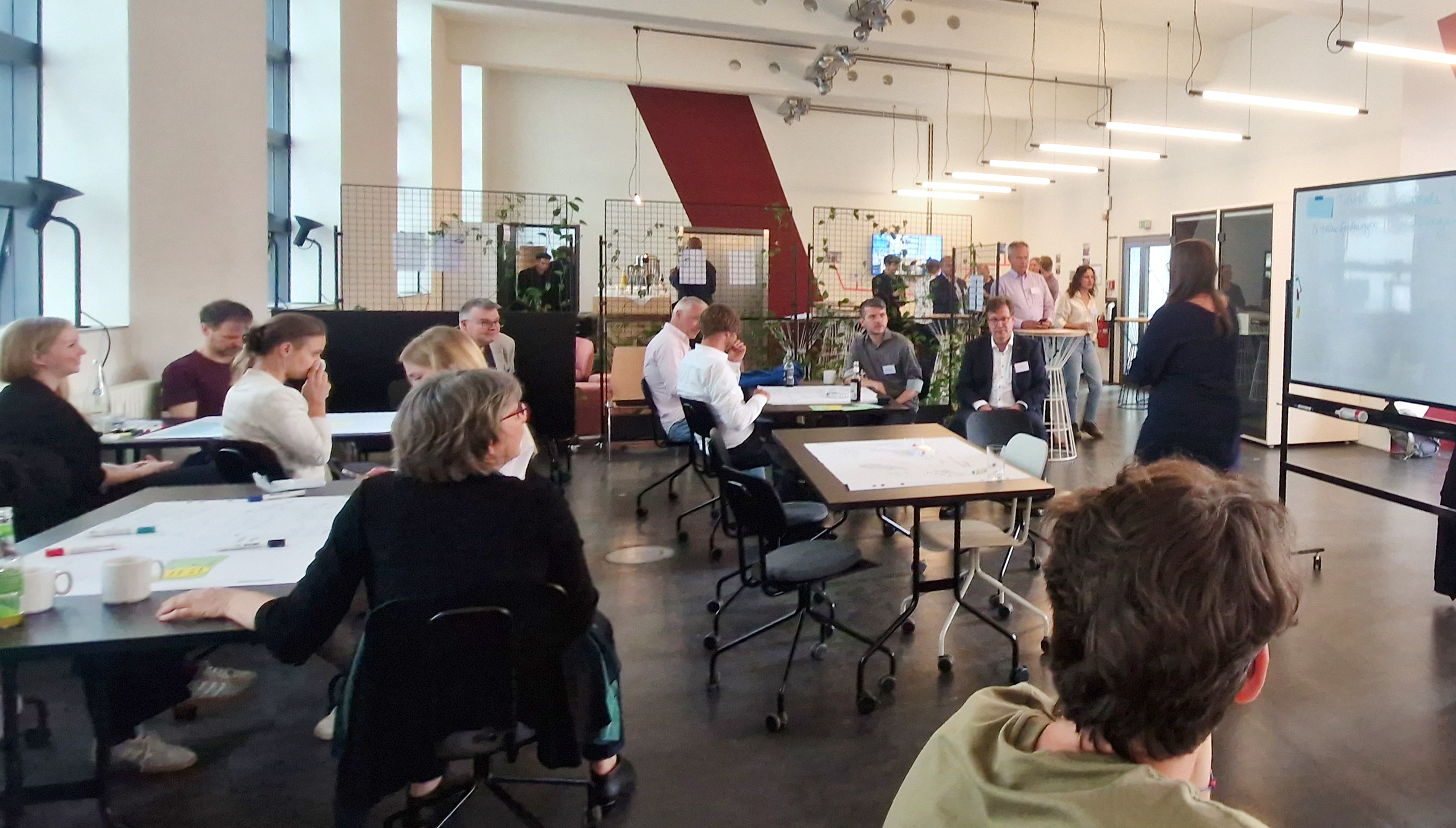 Workshop-Situation: mehrere Menschen sitzen an Tischen und erarbeiten Themen zur Relevanz der Cybersicherheit für kritische Infrastrukturen