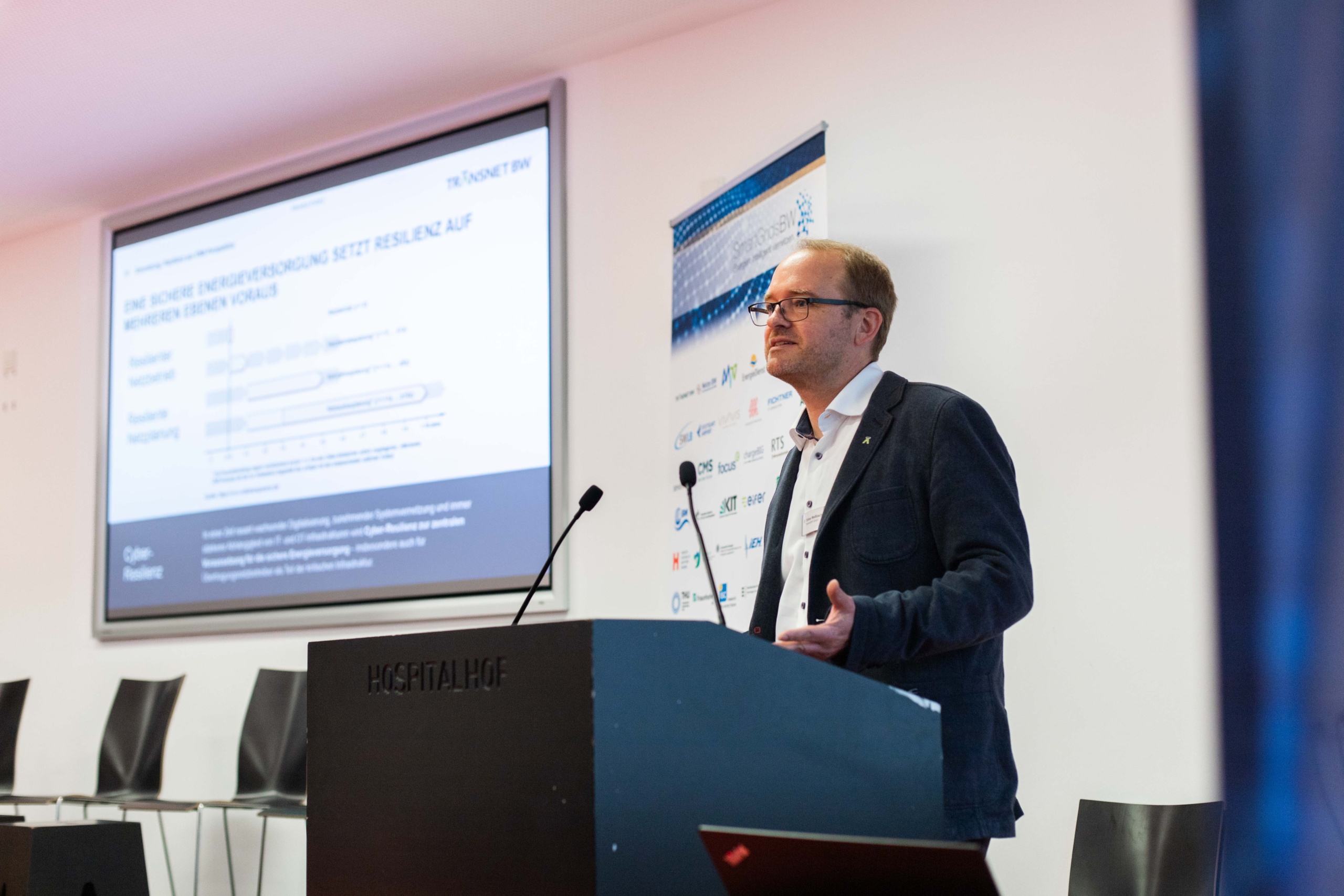 Foto: SmartGridsBW (Lea-Philine Beyer) Smart Grids-Gespräche zum Thema Resilienz: Wie wir kritische Infrastrukturen sichern können. Referent Tobias Weissbach am Rednerpult.