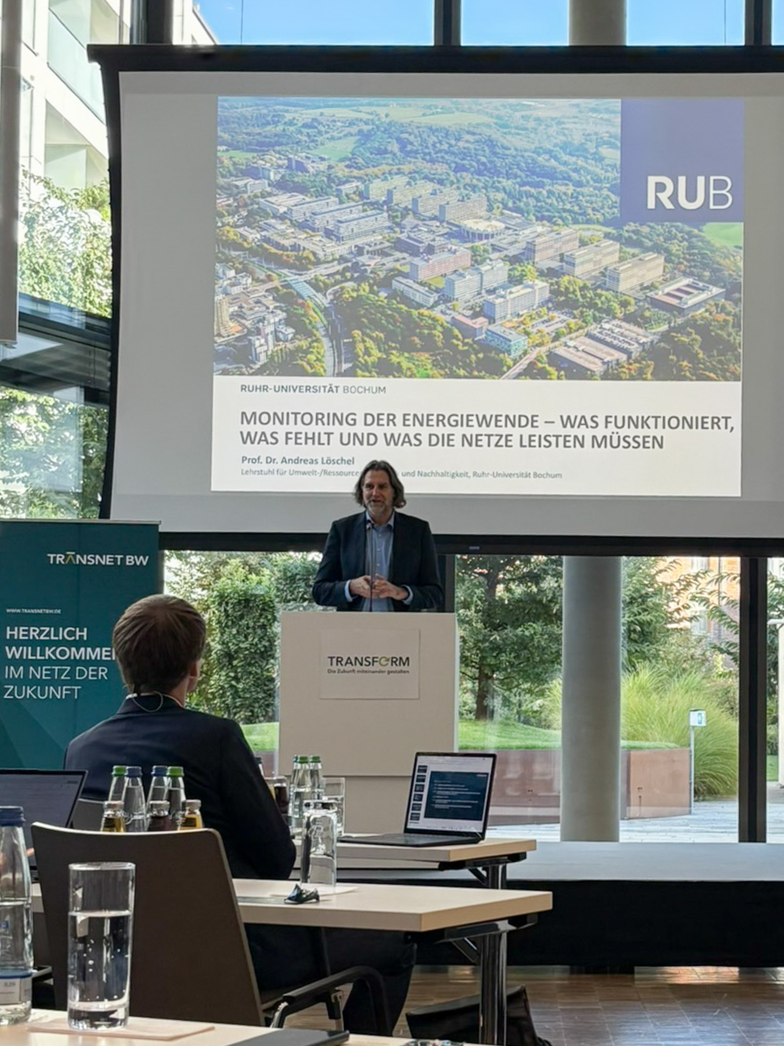 Vortragende Person am Pult präsentiert ein Monitoring-Projekt zur Energiewende mit Folien der Ruhr-Universität Bochum.