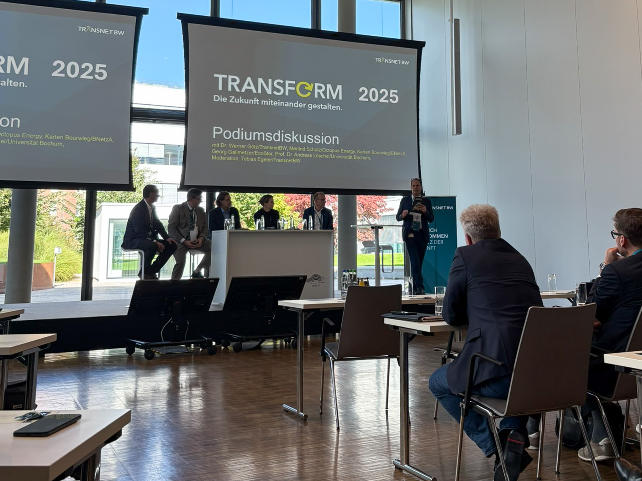 Diskussionsteilnehmende und Publikum während der Podiumsdiskussion bei der Veranstaltung TRANSFORM 2025.