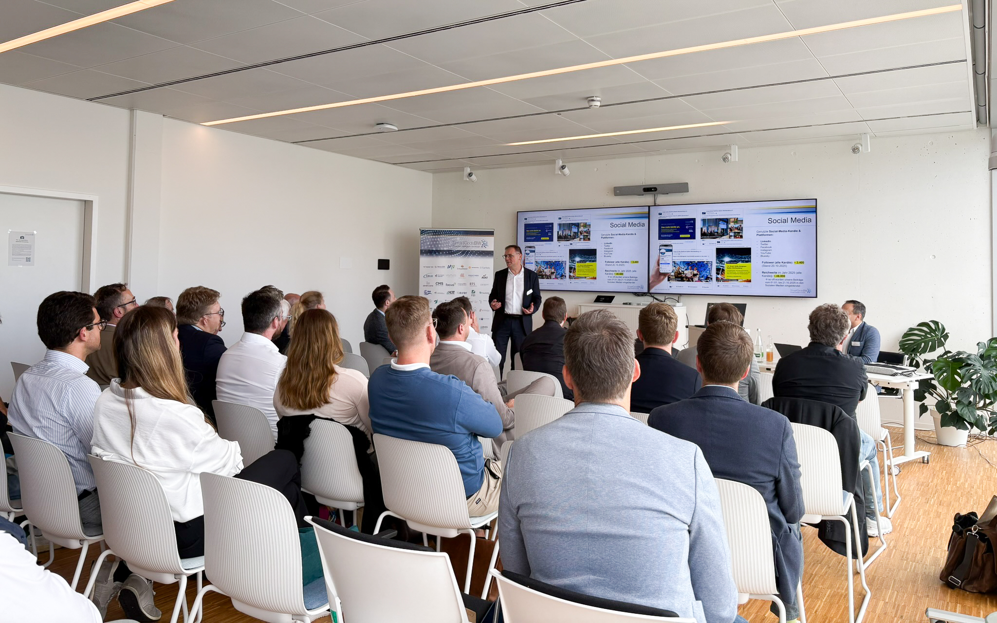 Vortrag während der SmartGridsBW-Gespräche 2025: Ein Referent stellt Kennzahlen zur SmartGridsBW-Webseite vor, während Teilnehmende aufmerksam zuhören.