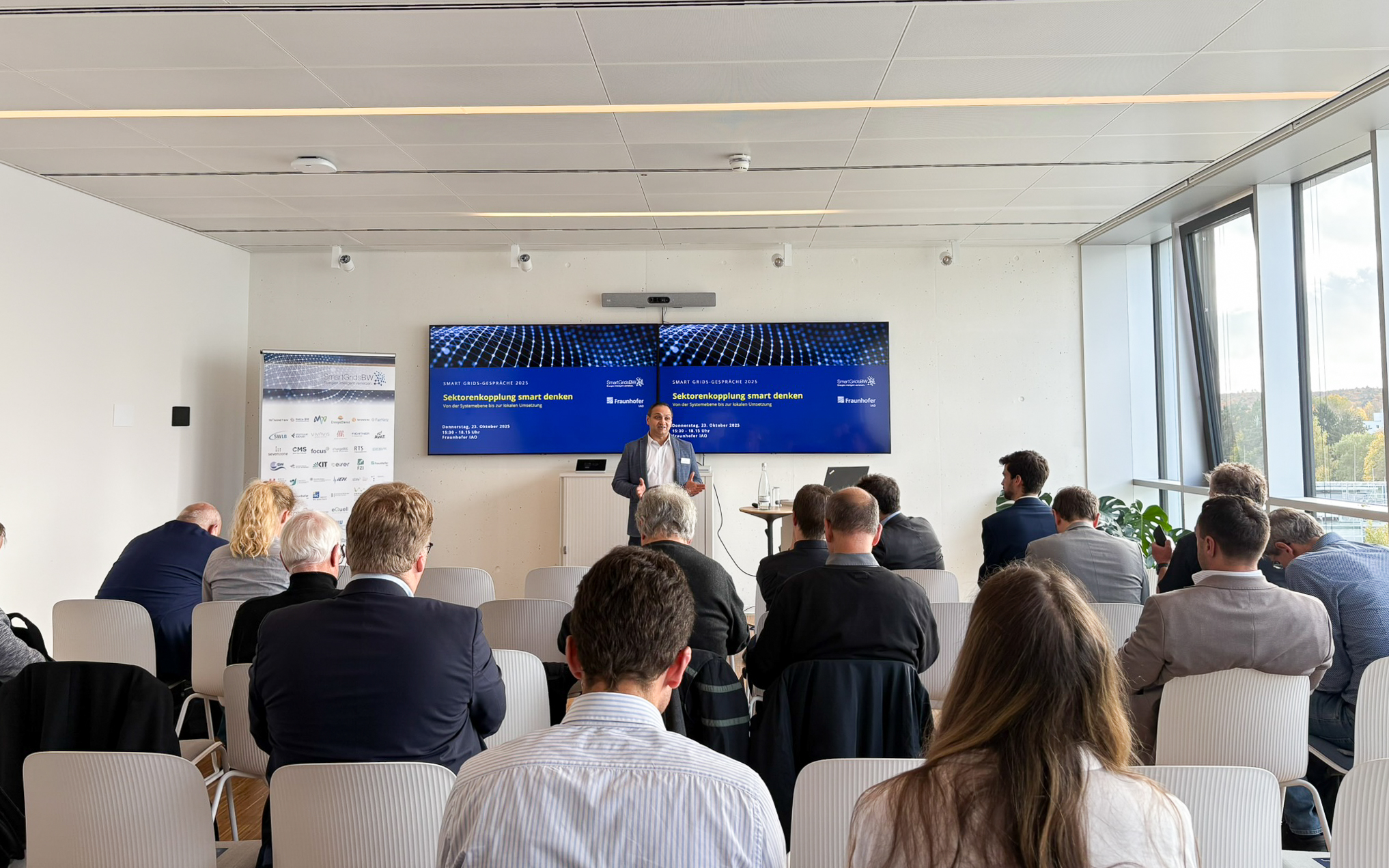 Vortrag während der SmartGridsBW-Gespräche 2025: Ein Referent stellt Kennzahlen zur SmartGridsBW-Webseite vor, während Teilnehmende aufmerksam zuhören.