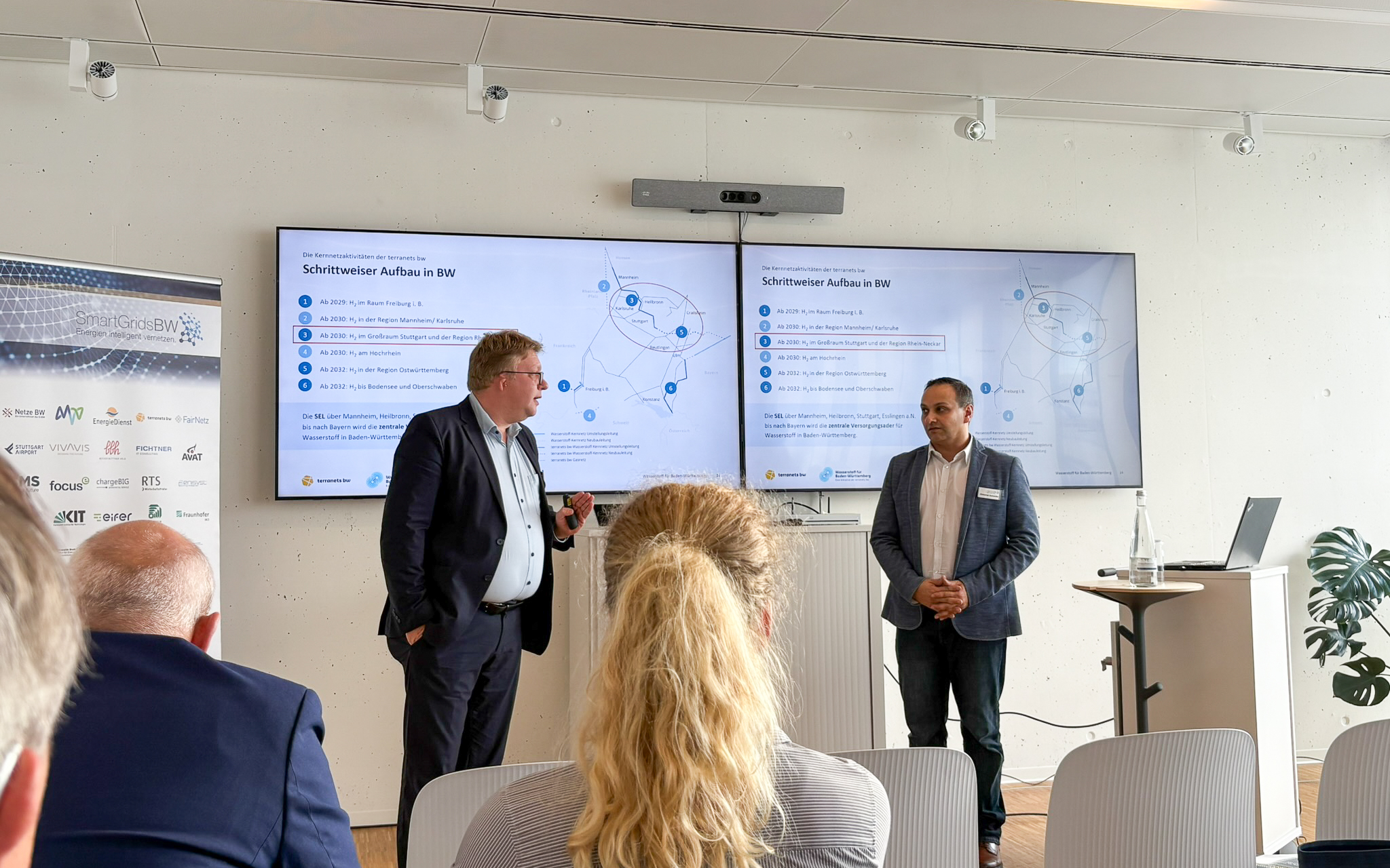 Vortrag während der SmartGridsBW-Gespräche 2025: Ein Referent stellt Kennzahlen zur SmartGridsBW-Webseite vor, während Teilnehmende aufmerksam zuhören.