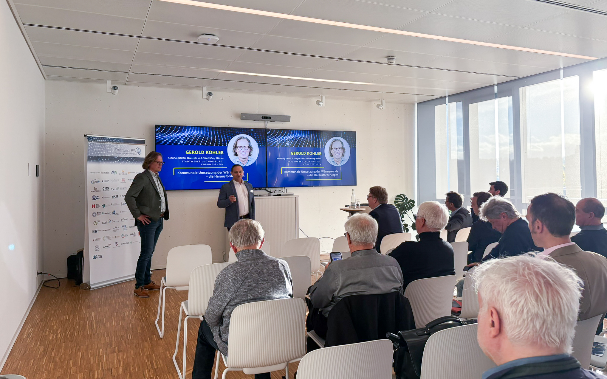 Vortrag während der SmartGridsBW-Gespräche 2025: Ein Referent stellt Kennzahlen zur SmartGridsBW-Webseite vor, während Teilnehmende aufmerksam zuhören.