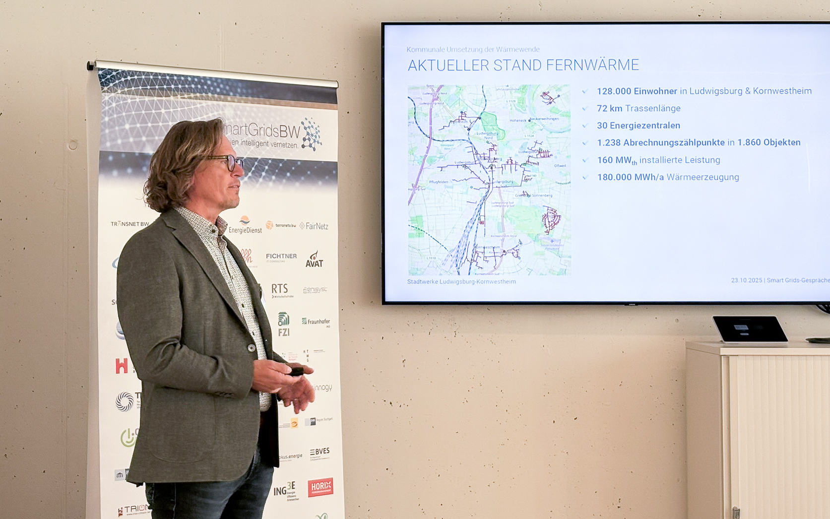 Vortrag während der SmartGridsBW-Gespräche 2025: Ein Referent stellt Kennzahlen zur SmartGridsBW-Webseite vor, während Teilnehmende aufmerksam zuhören.