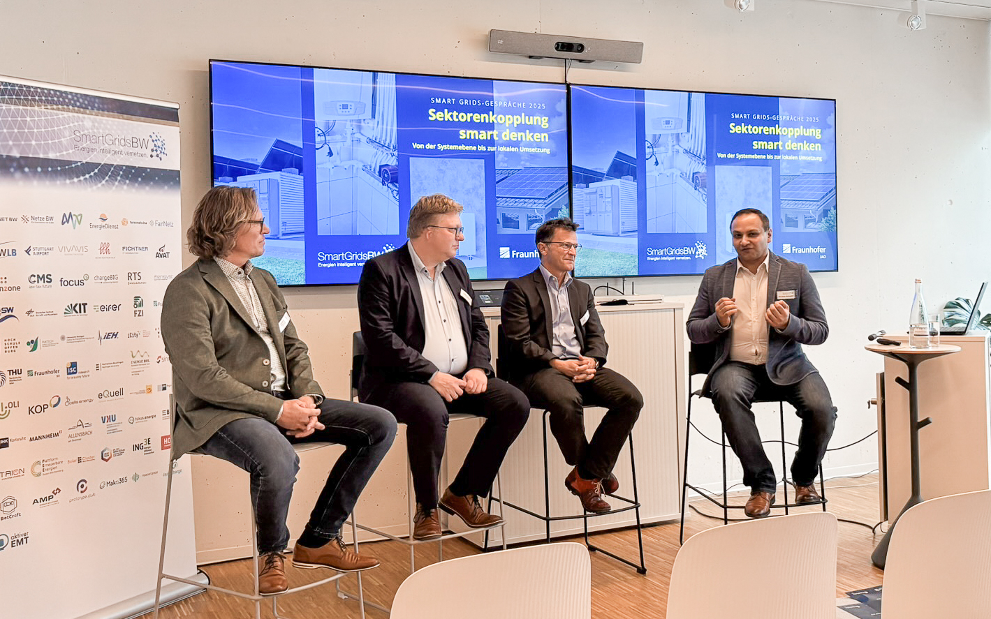 Podiumsdiskussion bei den SmartGridsBW-Gesprächen 2025: Vier Experten diskutieren das Thema „Sektorenkopplung smart denken“ vor Publikum.