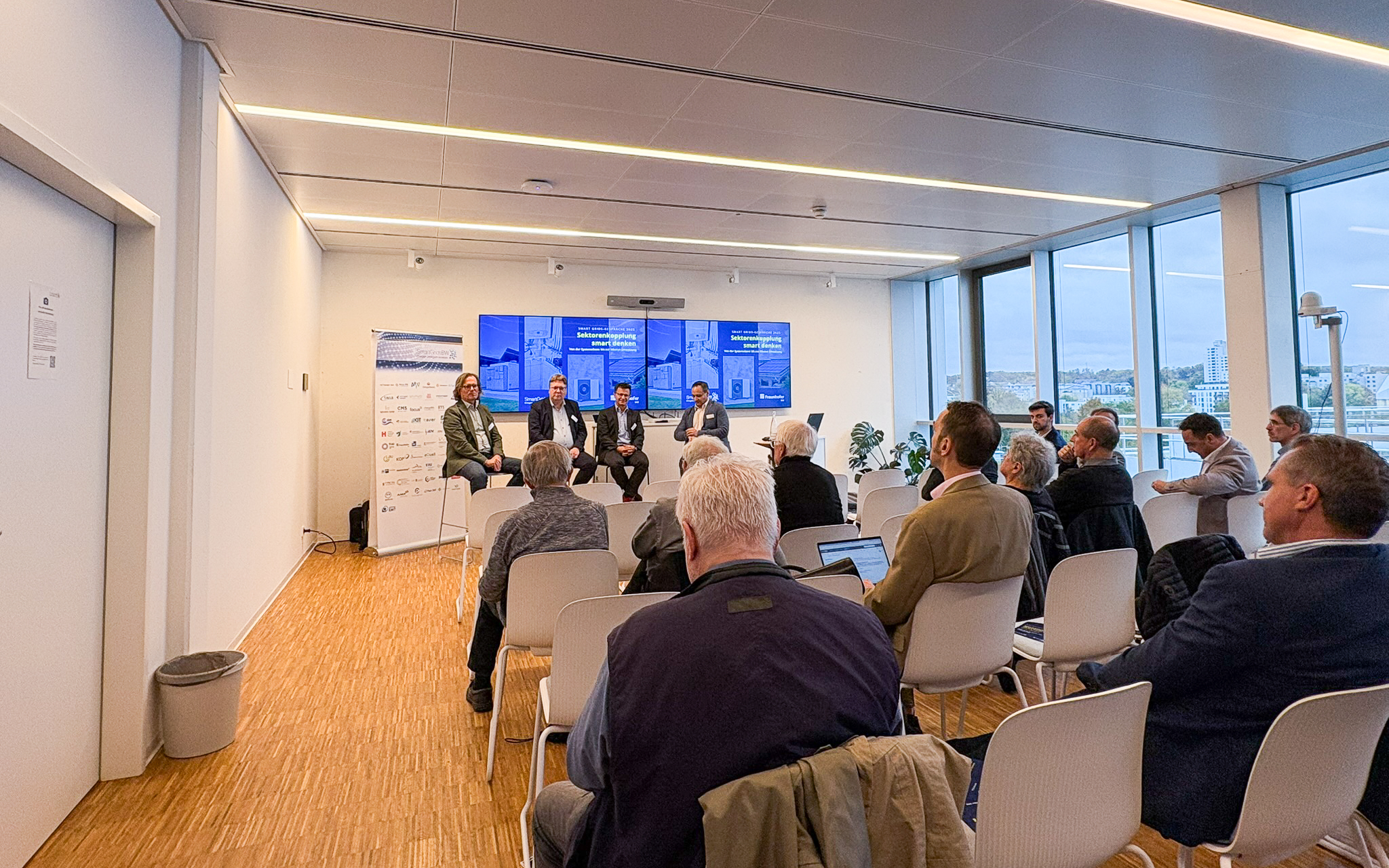 Podiumsdiskussion bei den SmartGridsBW-Gesprächen 2025: Vier Experten diskutieren das Thema „Sektorenkopplung smart denken“ vor Publikum.