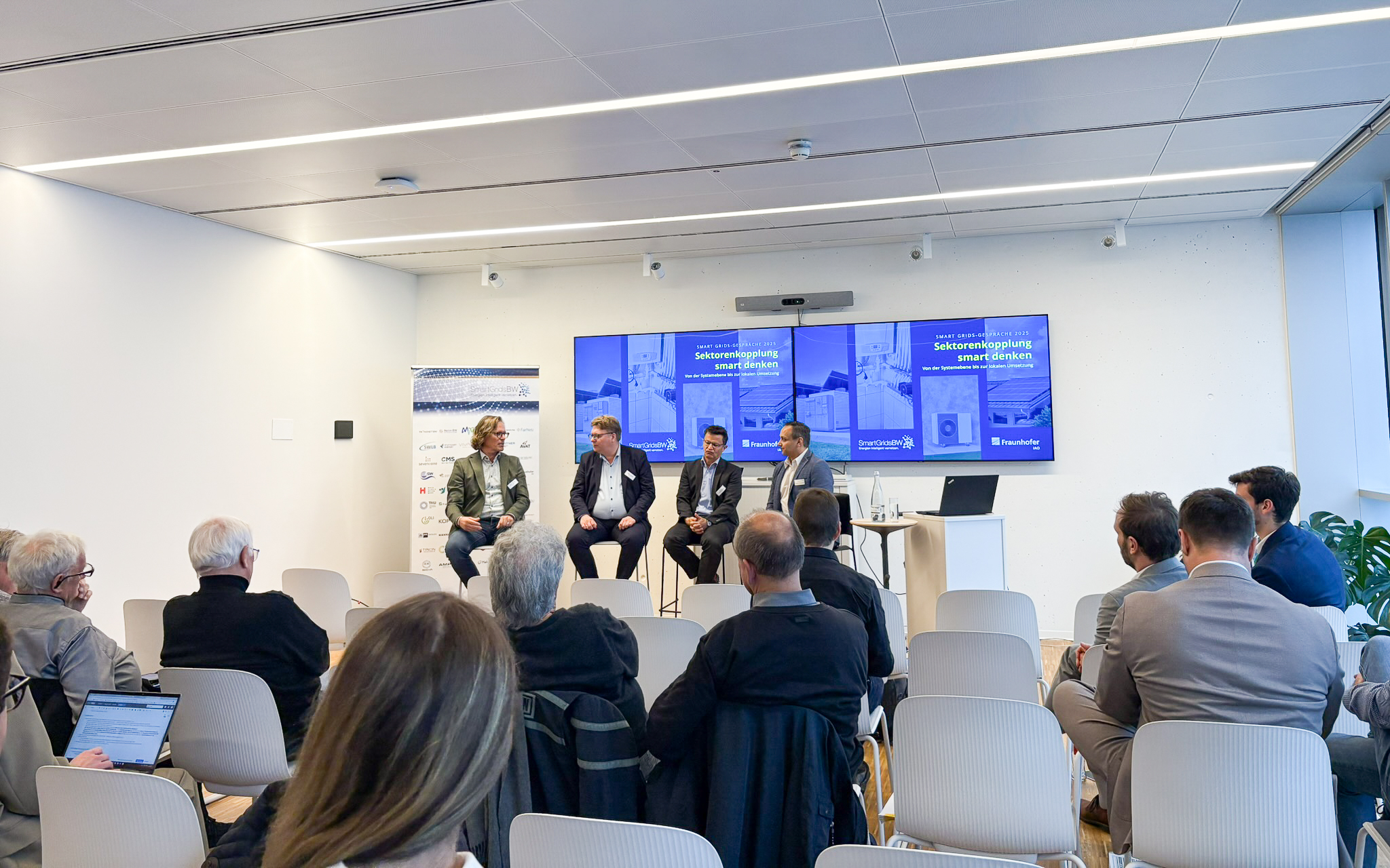 Podiumsdiskussion bei den SmartGridsBW-Gesprächen 2025: Vier Experten diskutieren das Thema „Sektorenkopplung smart denken“ vor Publikum.