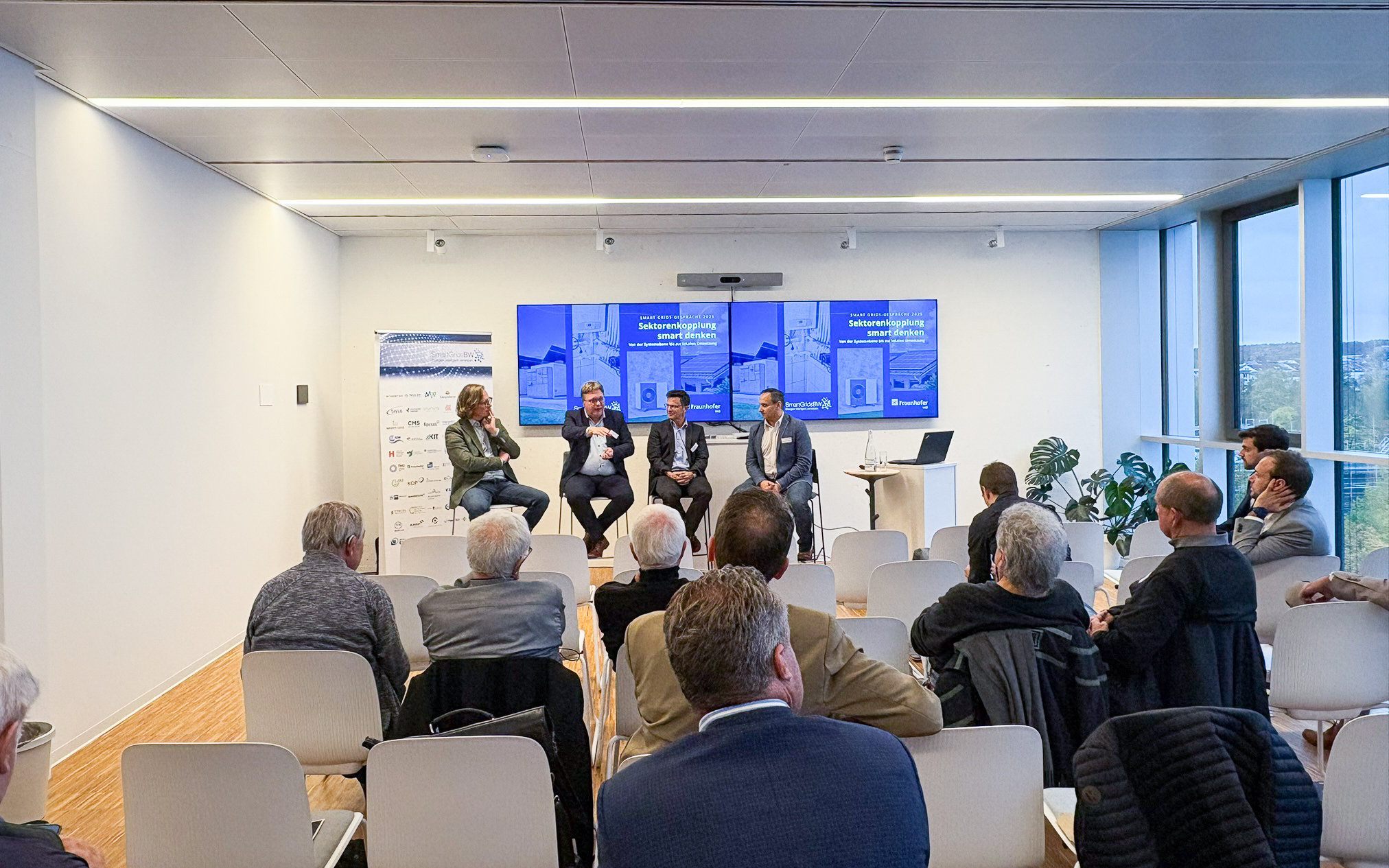 Podiumsdiskussion bei den SmartGridsBW-Gesprächen 2025: Vier Experten diskutieren das Thema „Sektorenkopplung smart denken“ vor Publikum.