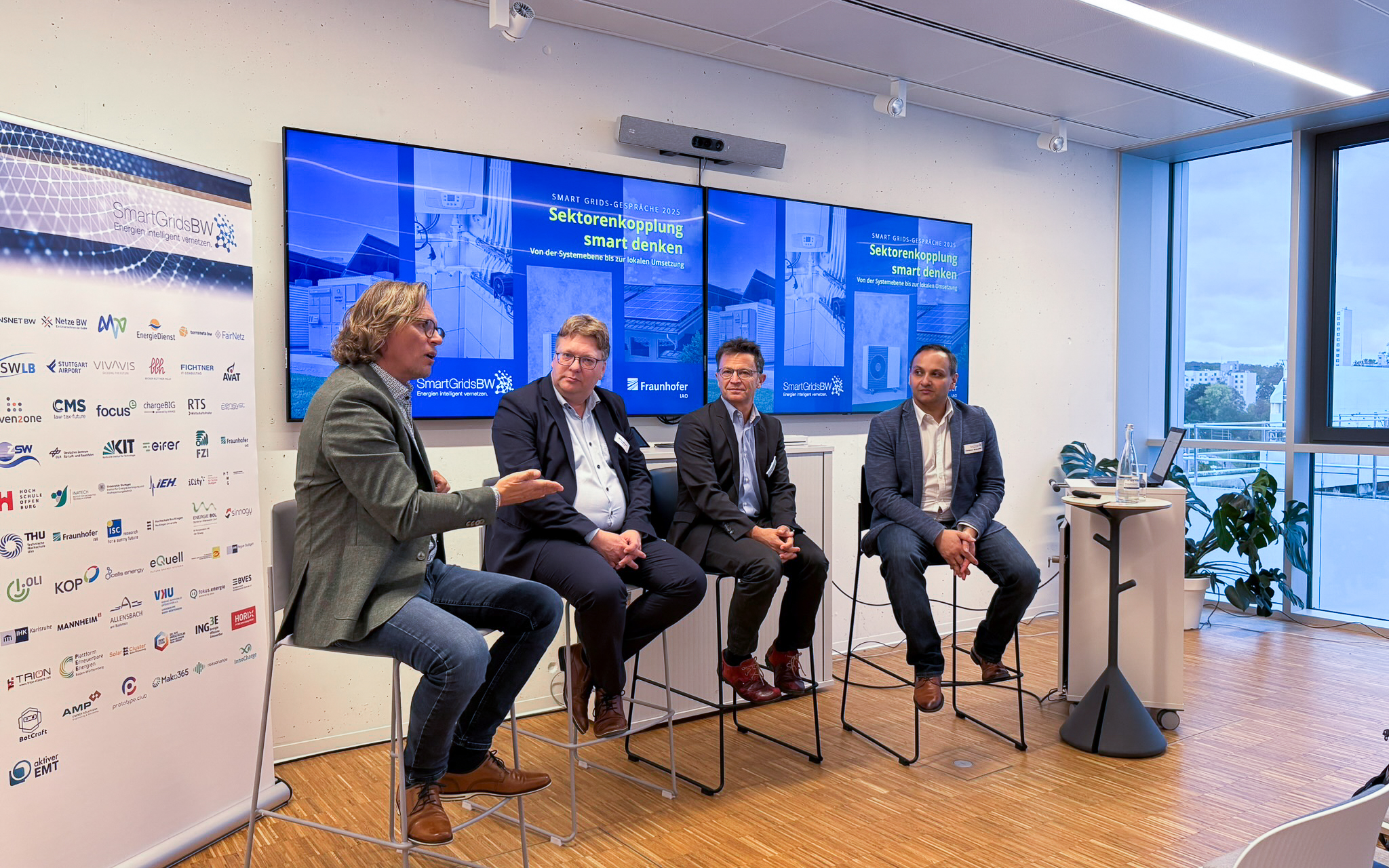 Podiumsdiskussion bei den SmartGridsBW-Gesprächen 2025: Vier Experten diskutieren das Thema „Sektorenkopplung smart denken“ vor Publikum.