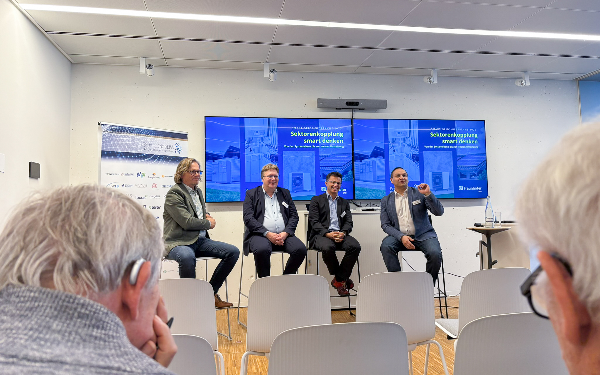 Podiumsdiskussion bei den SmartGridsBW-Gesprächen 2025: Vier Experten diskutieren das Thema „Sektorenkopplung smart denken“ vor Publikum.